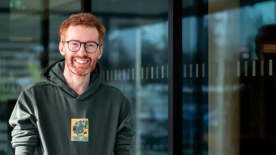 Portrait of Ryan, reflected in the window pane of a scientific institute