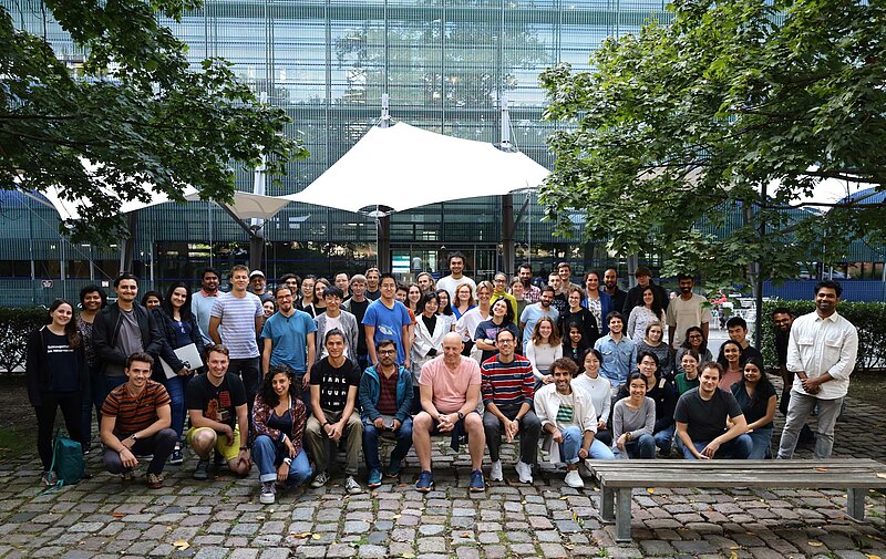 A crowd of people stand outside the MPI-CBG smiling 