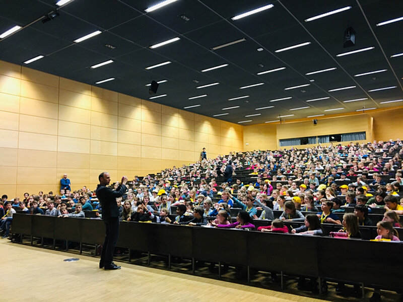Stephan Grill talks in front of 500 curious kids inside a lecture hall