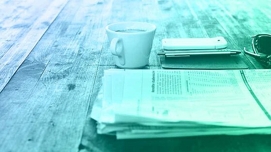 PoL Public Relations Coffee, smartphone, and newspaper on a wooden table