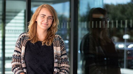 Portrait of Carolin Weichelt, reflected in the window pane of a scientific institute