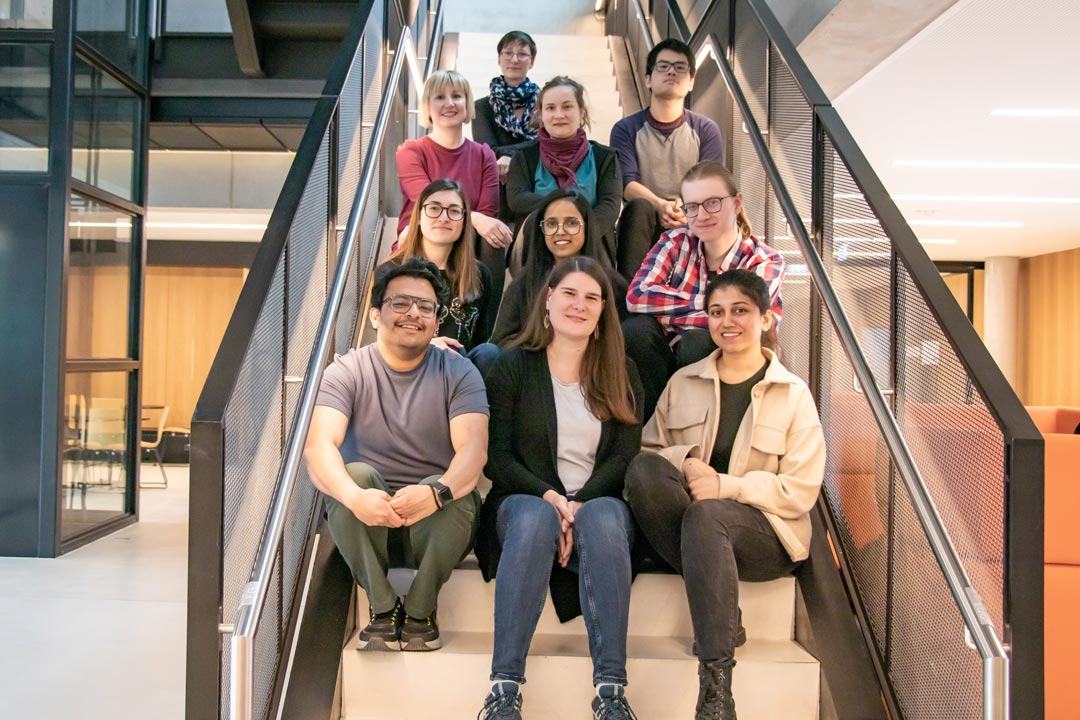 Ten people sitting on stairs in the atrium of a modern scientific institute