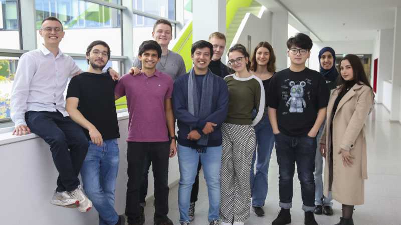 A group of 11 young people in the hallway of a scientific institute