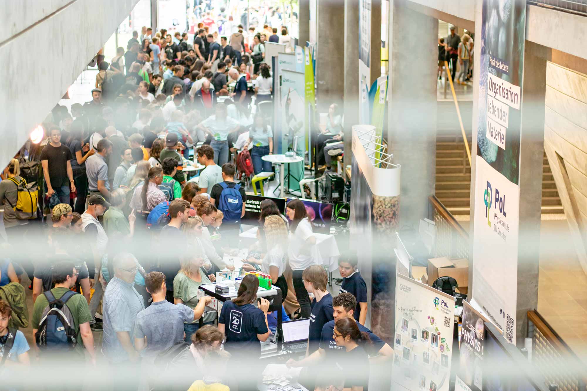 Many people in a large vestibule of a building, seen from a level above